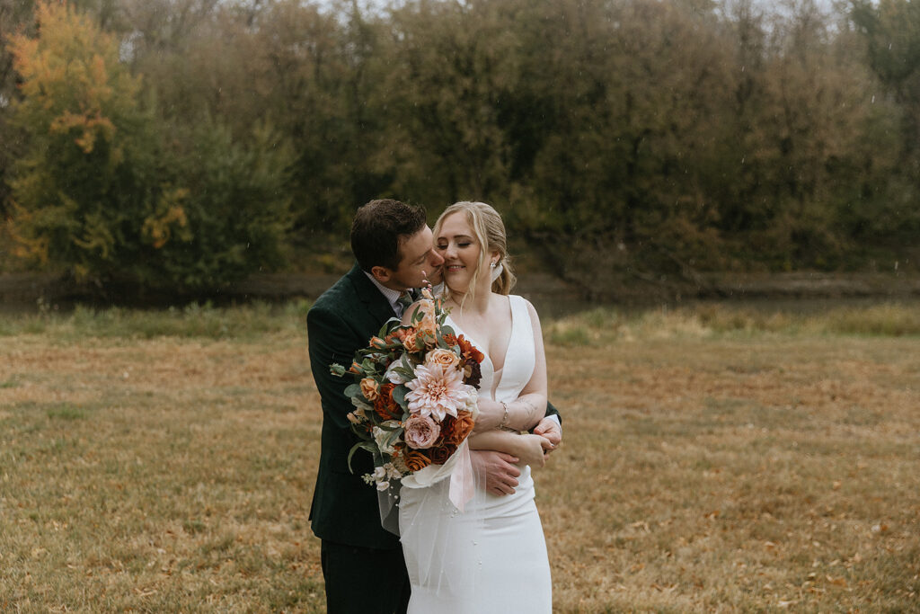 picture of the groom kissing the bride on the cheek