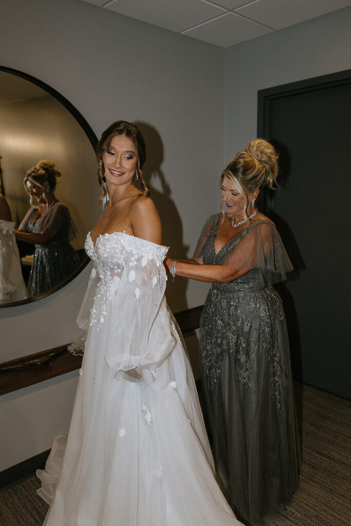 mother of the bride helping the bride with her wedding dress