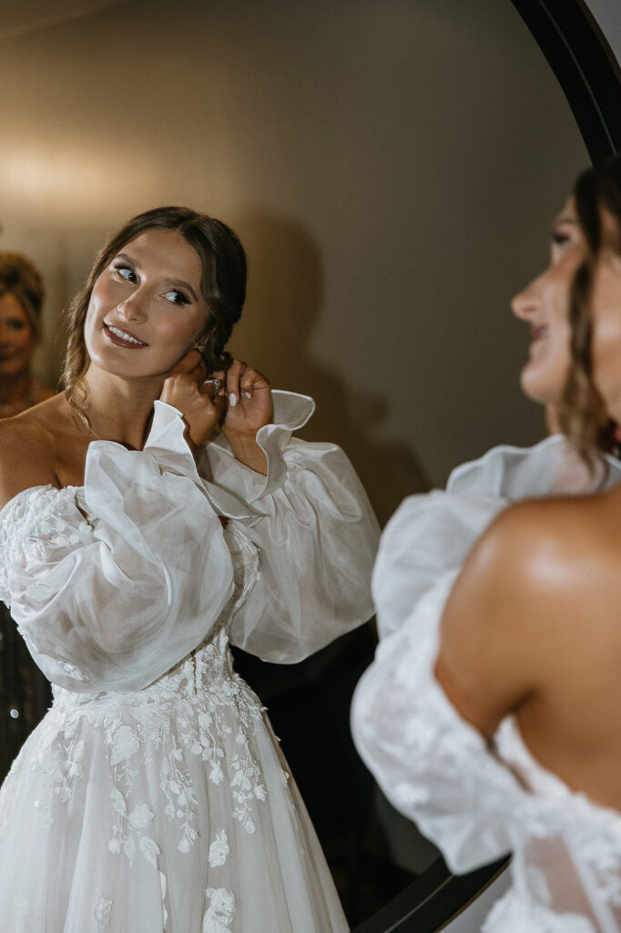 bride putting on her jewelry before the ceremony