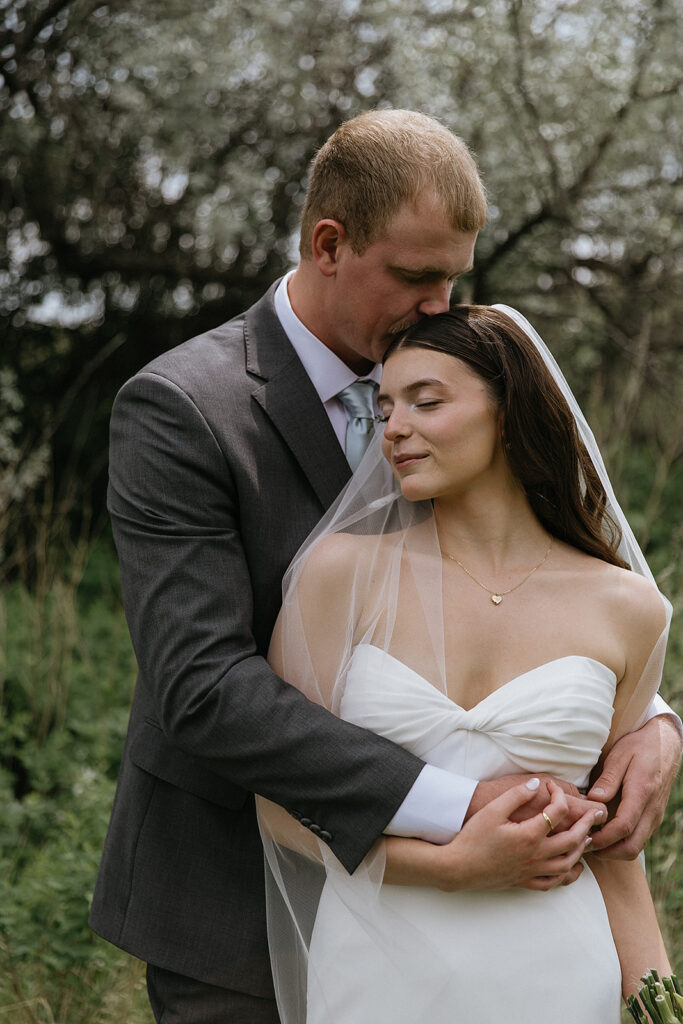 Groom, kissing the bride on the forehead
