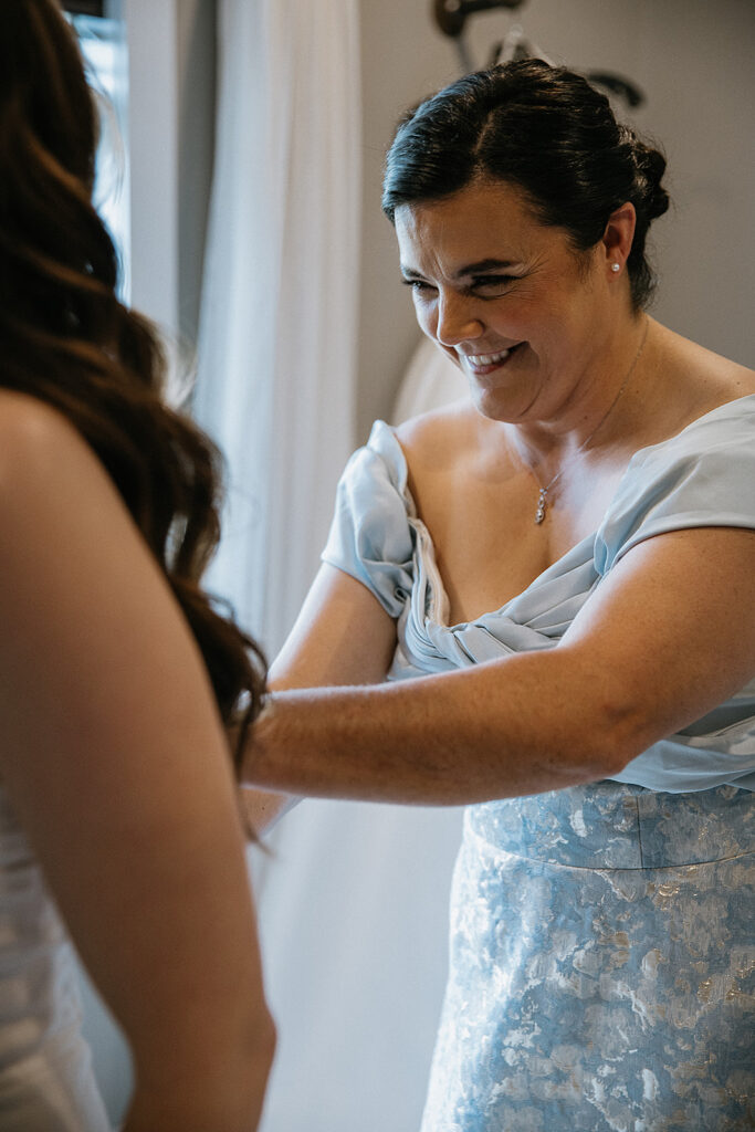 Mother of the bride helping her with her wedding dress