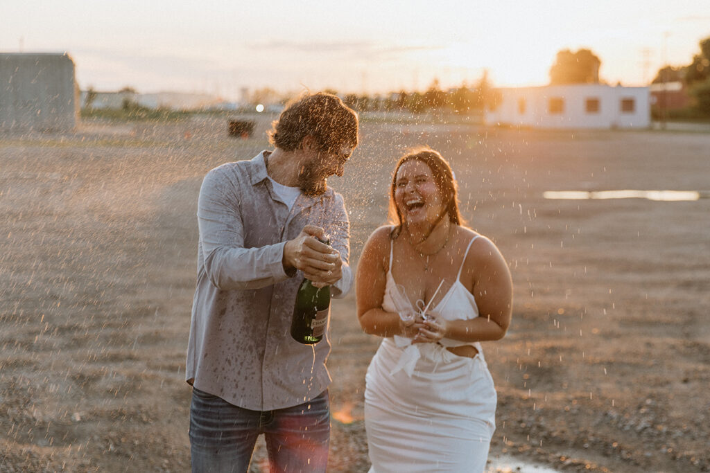 couple celebrating their engagement with a champagne pop