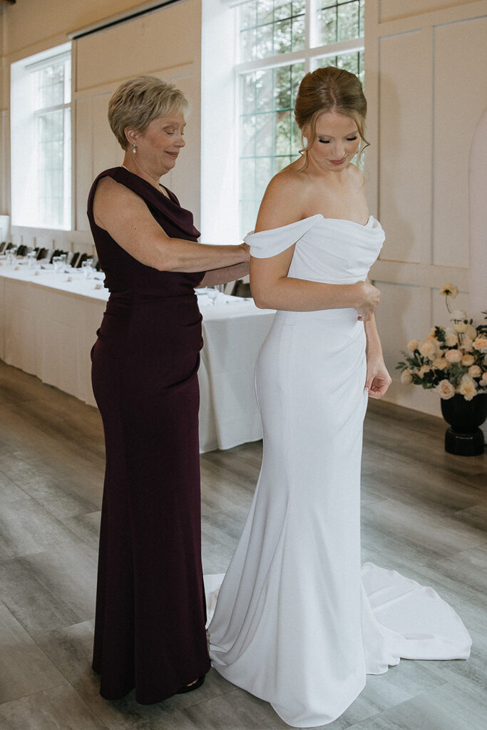 mother of the bride helping her with the wedding dress