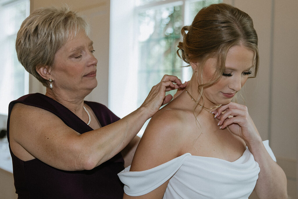 mother of the bride helping her with her jewelry
