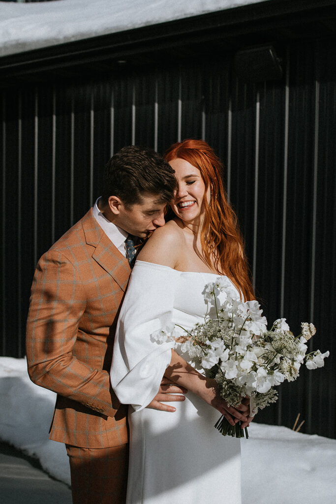 groom kissing the bride on the shoulder
