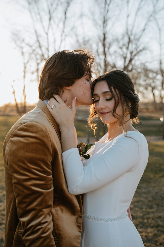 groom kissing the bride on the forehead