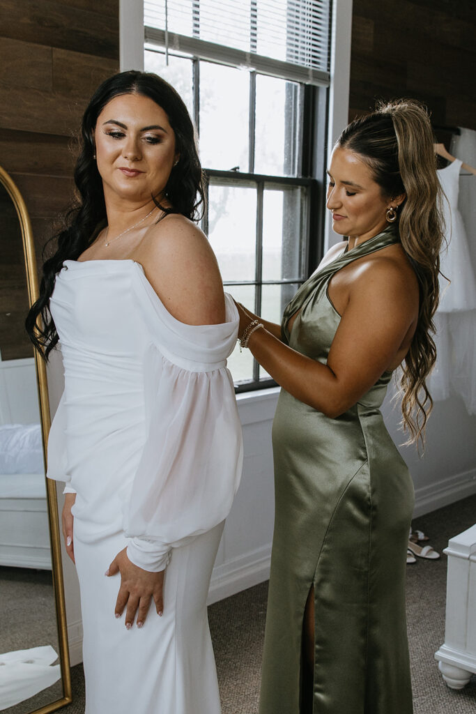 bridesmaid helping the bride with her wedding dress