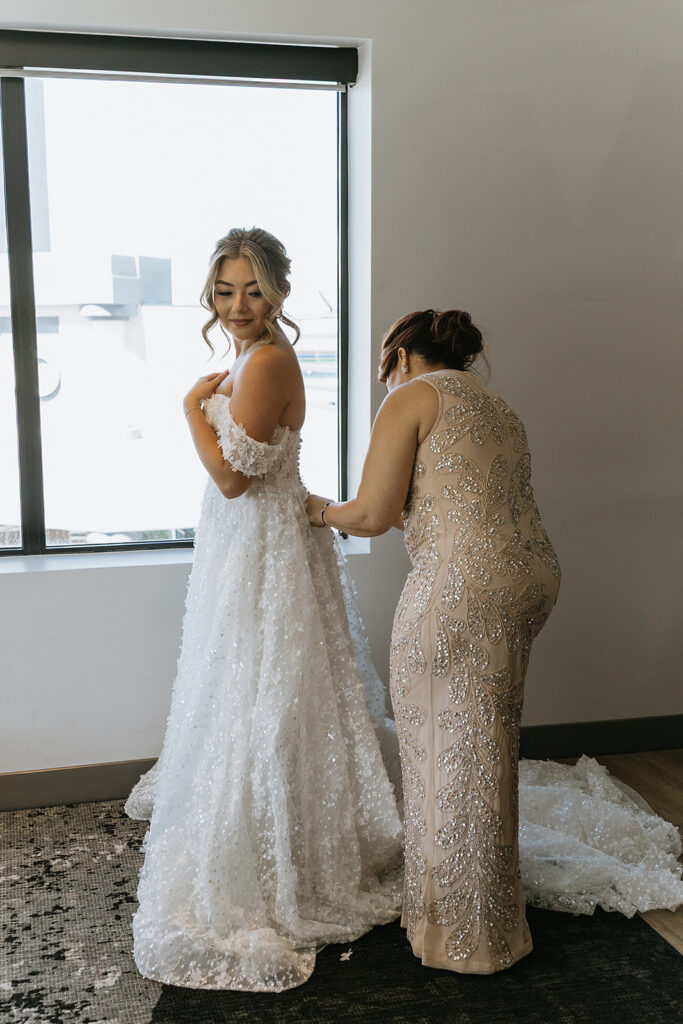 mother of the bride helping her with her wedding dress